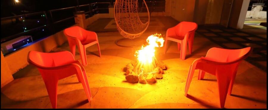 Bonfire glowing at night with lounge chairs around it