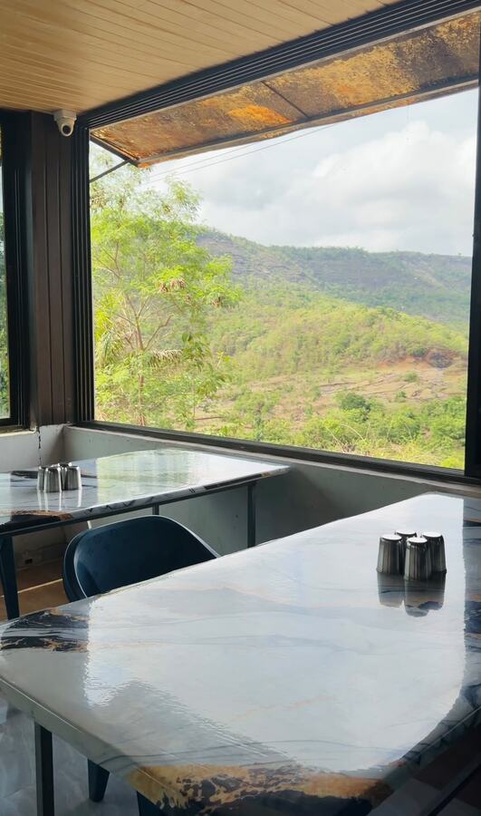 Nakshatra Villa dining tables beside a mountain-view window
